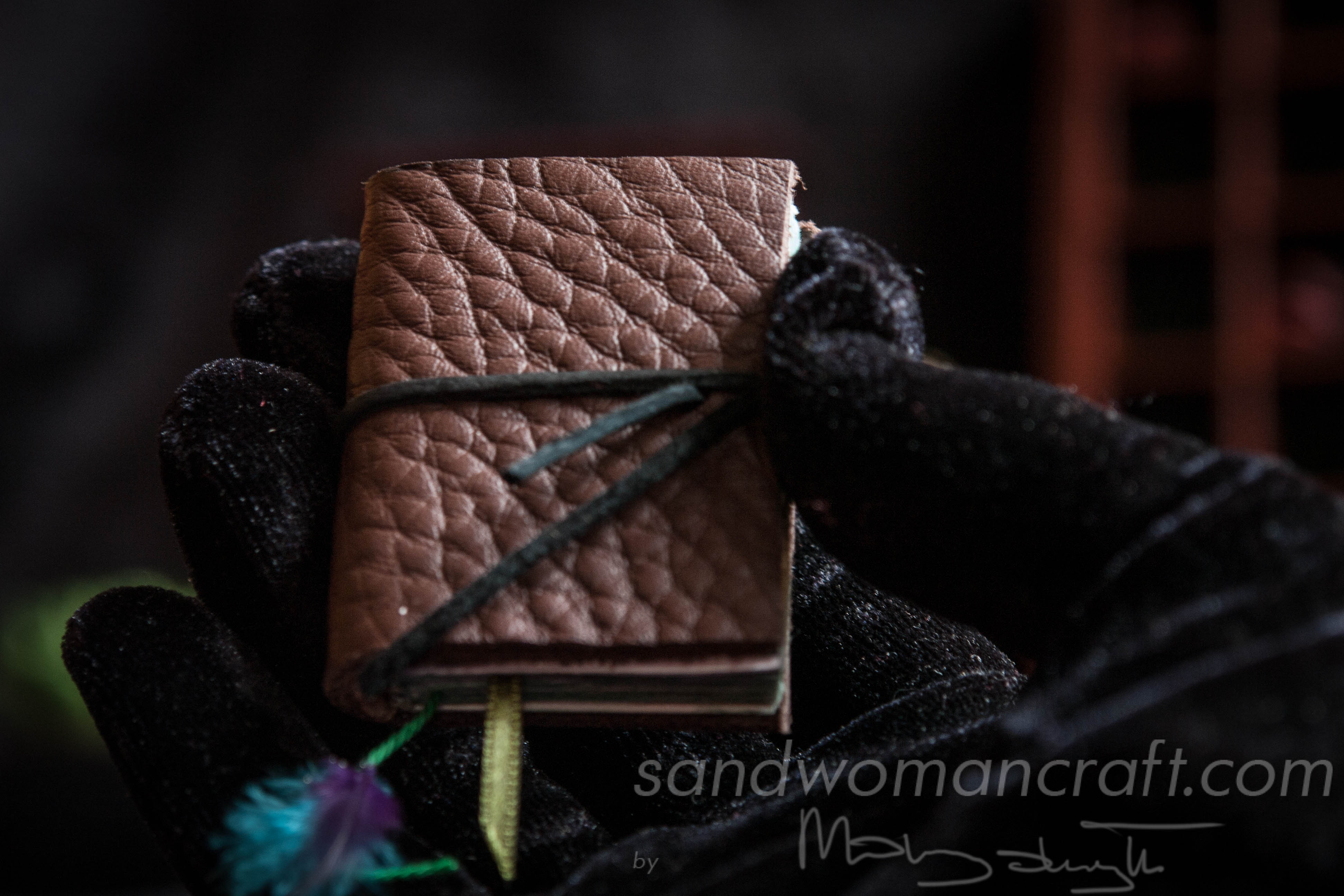 Miniature book. Brown leather with feather