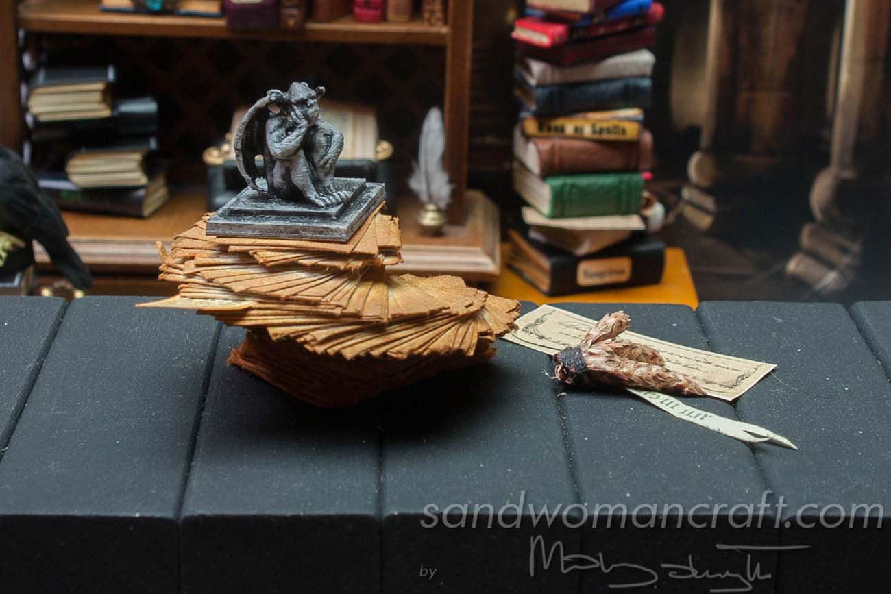 Miniature stack of aged papers with Gargoyle figurine protecting it