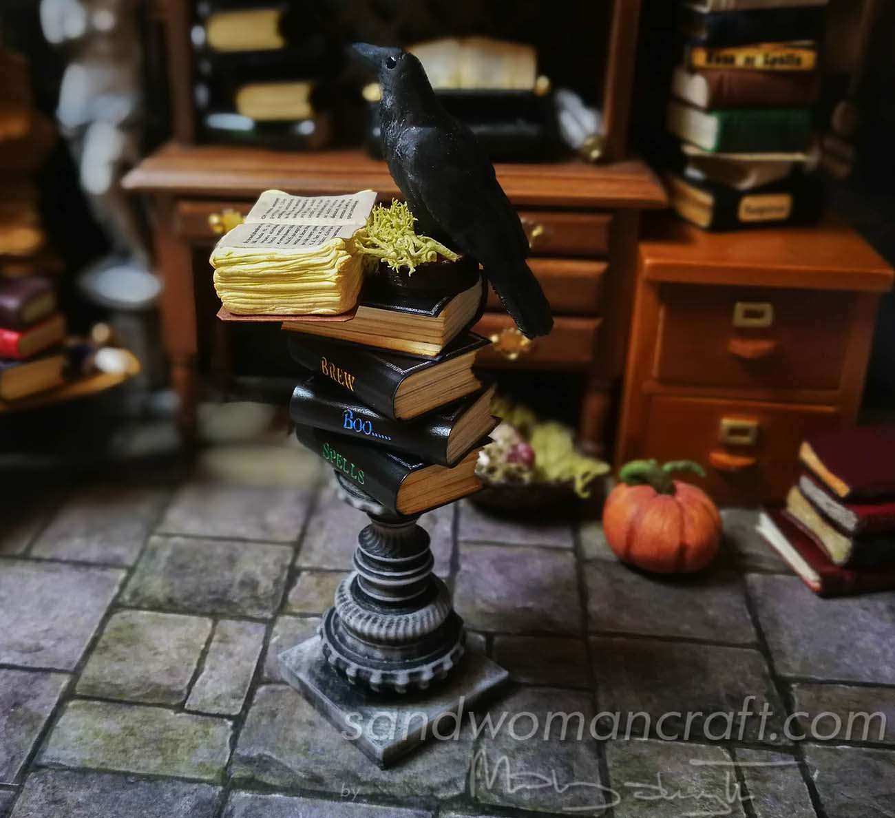 Stack of miniature books with a miniature open book and Crow at the top